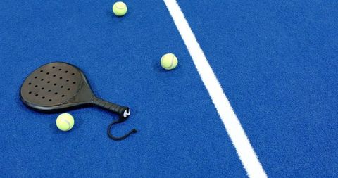 Black Padel Racket on Blue Court with Tennis Balls