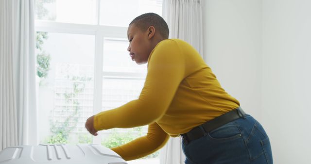 Woman in yellow shirt ironing clothes in bright room - Download Free Stock Images Pikwizard.com