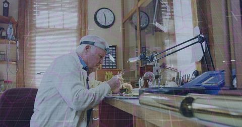 Repairing senior watchmaker assembling brass movement at workbench in vintage workshop