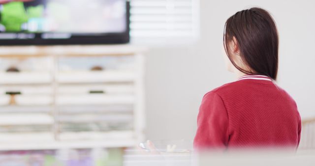 Caucasian woman sitting on couch, eating snacks and watching tv in living room - Download Free Stock Photos Pikwizard.com
