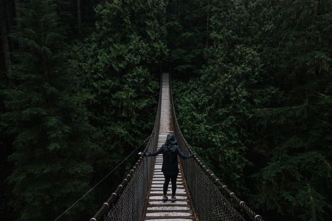 Man Crossing Suspension Bridge in Dense Forest