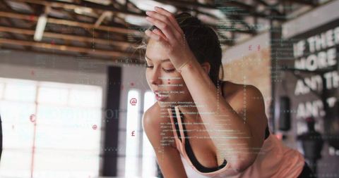 Exhausted athlete pausing to catch breath in industrial gym with floating code overlay
