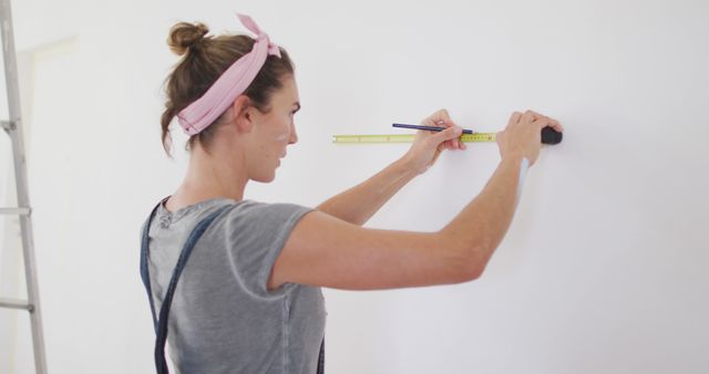Focused caucasian woman measuring walls with ruler. Lifestyle, domestic life, house interior and work, unaltered.