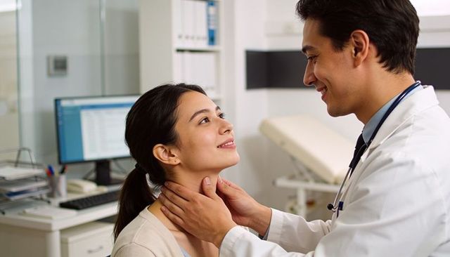 Doctor examining patient neck during routine checkup in clinic