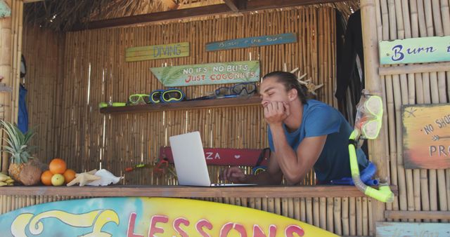 Young Man Working on Laptop at Outdoor Beach Shop - Download Free Stock Images Pikwizard.com