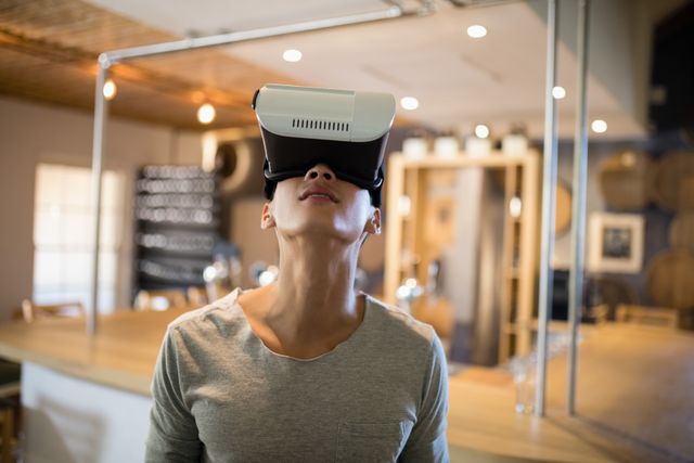 Man enjoying virtual reality experience in a modern restaurant. Ideal for use in articles or advertisements related to technology, virtual reality, modern dining experiences, and digital innovation.