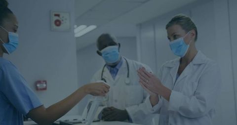 Nurse in Scrubs Passing Disinfectant to Doctor in Hospital