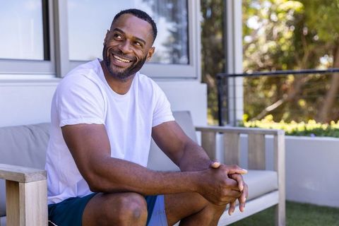 African american man relaxing on sunny patio smiling and enjoying outdoor serenity