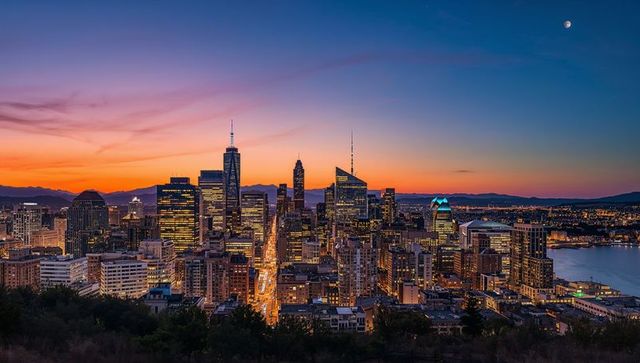 Twilight skyline glow over urban harbor showing illuminated avenue and modern highrises