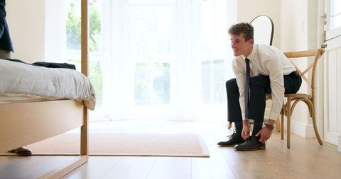Groom dressing for wedding with best man at home