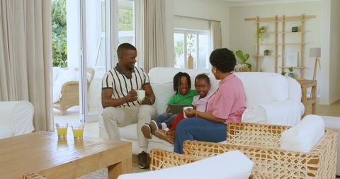 African American family relaxing on white sofa in bright coastal living room