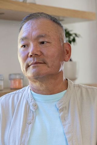 Senior asian man looking thoughtful in cozy kitchen with soft natural light
