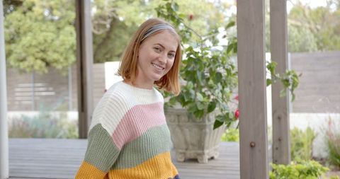 Smiling Woman Enjoying Outdoors in Colorful Knit Sweater on Backyard Deck