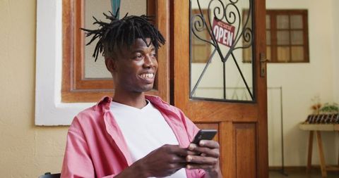 Smiling African American Craftsman Using Smartphone in Workshop