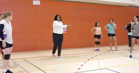 Female volleyball team training with african american coach guiding strategy and teamwork