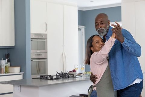 Senior african american couple dancing in modern kitchen sharing intimate home moment