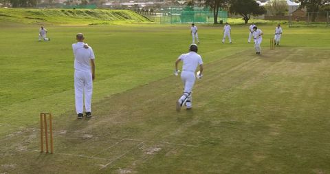 Outdoor Cricket Match with Batsman Running between Wickets