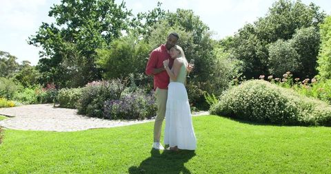 Smiling Couple Dancing on Sunny Day in Lush Garden