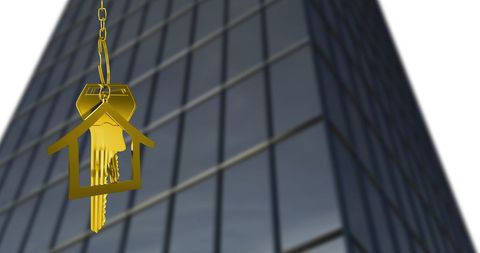 House Key Hanging Near Glass Building Symbolizing Real Estate Investment