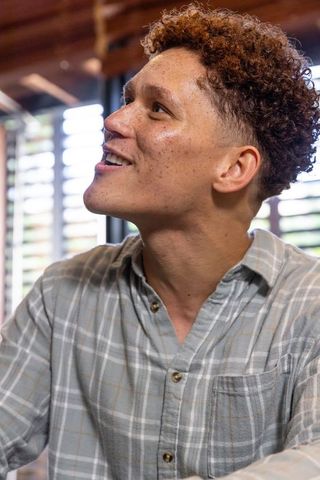 Man Contemplating in Cozy Room with Wooden Ceiling Beams