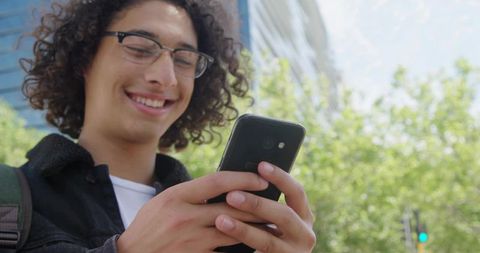 Cheerful Young Man Using Smartphone in Urban Outdoors