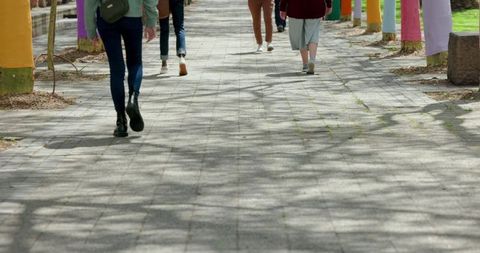 Walking away on urban promenade with colorful tree trunks and casual sneakers