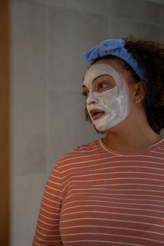 African american woman relaxing with facial mask in bathroom