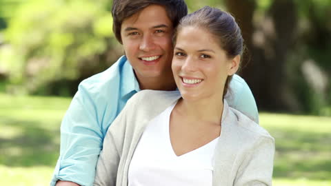 Happy Couple Relaxing on Grass in Blooming Garden