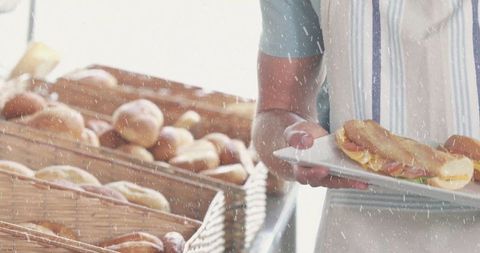 Bakery attendant displaying fresh artisan sandwich