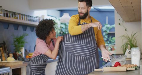 Happy Diverse Couple Cooking Together Wearing Aprons in Modern Kitchen - Download Free Stock Images Pikwizard.com