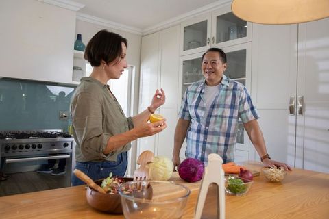 Diverse couple preparing fresh salad together in modern kitchen