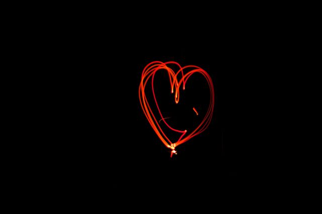 Abstract heart-shaped light painting on dark black background. Ideal for creative projects, Valentine's Day content, romantic themes, and product backgrounds highlighting love or light. Great for advertising campaigns promoting creativity and passion.