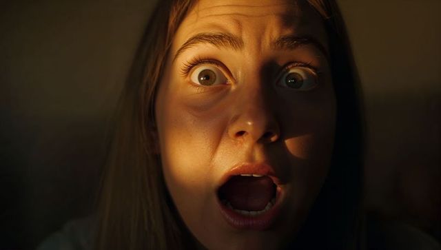 Woman showing shocked expression in dramatic warm sidelight closeup, cinematic portrait