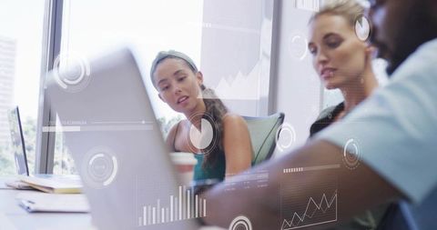 Team collaborating around laptop with digital analytics overlays visualizing business data