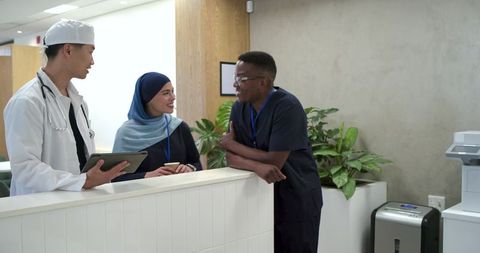 Diverse medical team collaborating at clinic reception with tablet and stethoscope