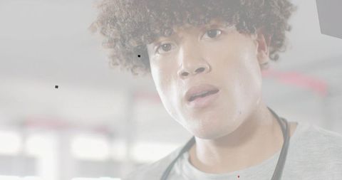Curly young man studying film lighting while inspecting black artifacts in workshop