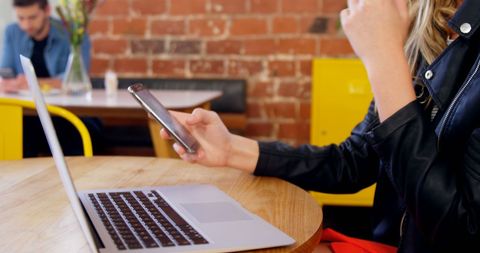 Woman Multitasking at Cozy Workspace with Laptop and Smartphone