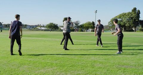 Playing catch on sunny community sports field with friends practicing teamwork and skills