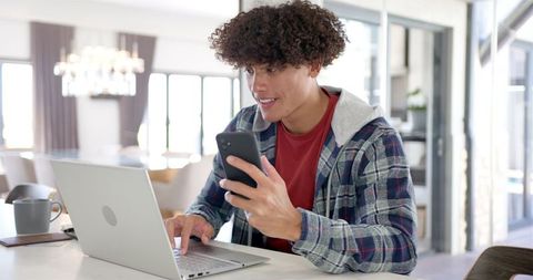 Young Adult Engaged with Laptop and Smartphone in Modern Home - Download Free Stock Images Pikwizard.com
