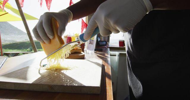 Hands wearing gloves grating cheese in a sunny kitchen - Download Free Stock Images Pikwizard.com