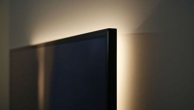 Backlit flat screen tv emitting warm led halo glow on wall for ambient lighting