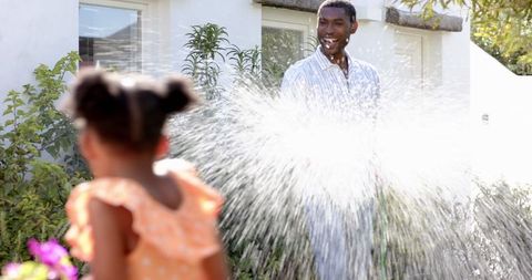 Joyful Father and Daughter Water Play in Sunny Garden
