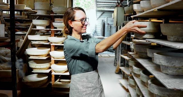 Female Potter Organizing Ceramic Bowls on Shelves in Studio - Download Free Stock Images Pikwizard.com