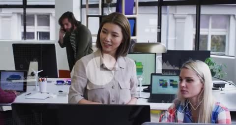 Female Colleagues Collaborating on Data Analysis in Modern Office