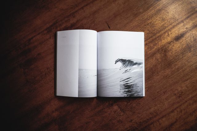 Open art book displaying wave illustration on wooden table, perfect for artistic and creative project concepts, design and interior decor inspiration, reading and literature themes.