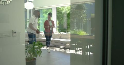 African american couple conversing in contemporary living room with glass doors and garden