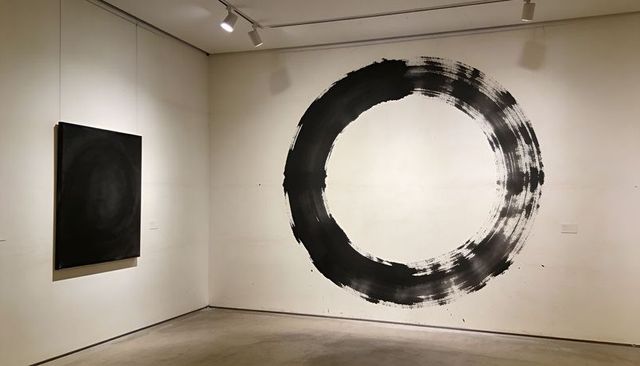Monochrome brushstroke circle mural on white gallery wall with minimalist black canvas