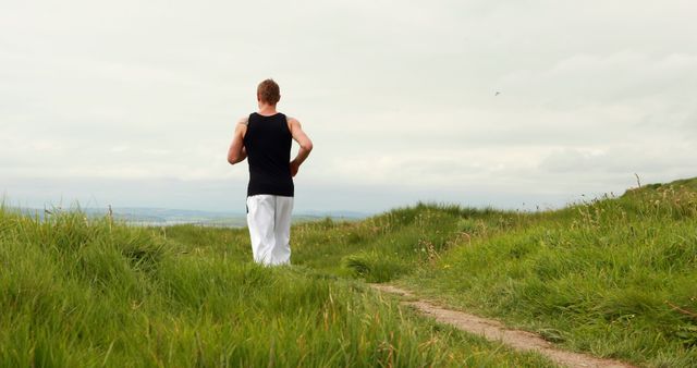 Man jogging on trail through grassy field - Download Free Stock Images Pikwizard.com