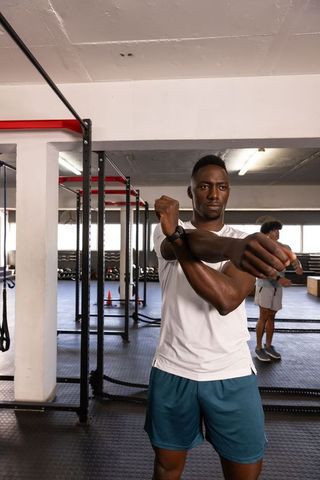 Diverse men preparing for workout in gym with pull-up rack and battle ropes