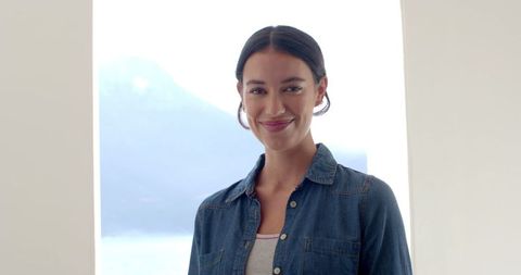 Smiling woman in denim shirt enjoying scenic coastal view